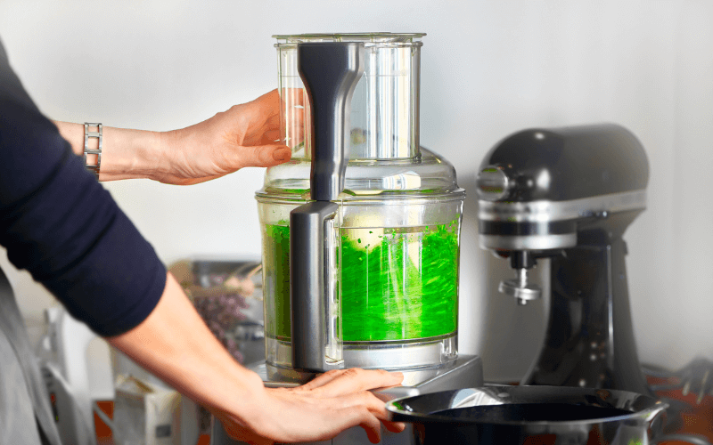 Image of a food processor being used, surrounded by different ingredients