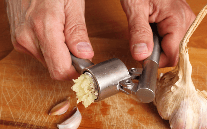 Image of a home cook using a garlic press