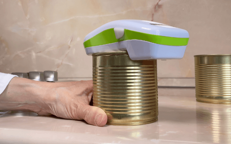 Image of an electric can opener, surrounded by different sized cans