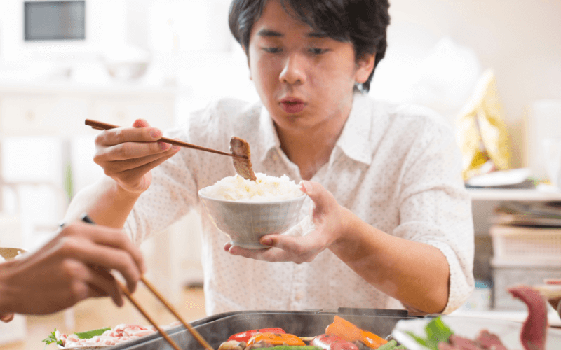 Image of a teenager eating a meat dish
