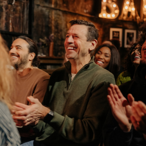 Small image of people laughing and smiling at a comedy club