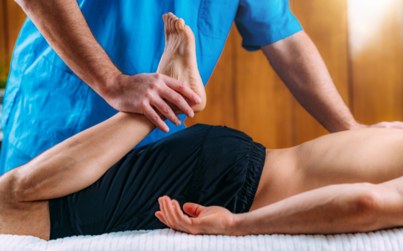 Image of a massage therapist lifting an athlete’s leg