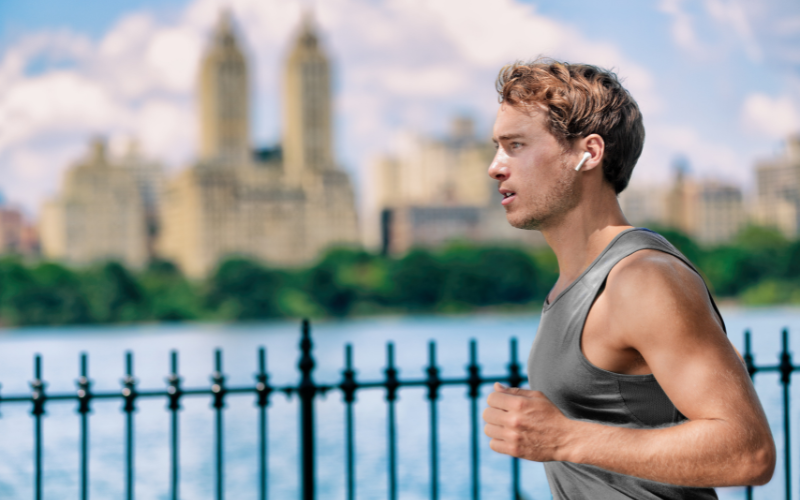 Image of a person running in the park with earbuds on