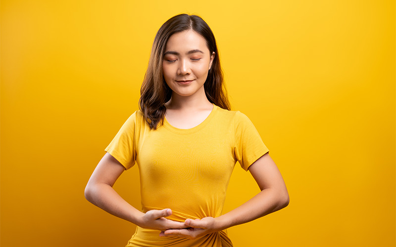 A person gently holding their stomach as if they just consumed something healthy.