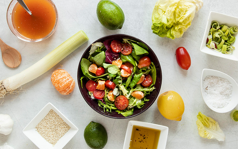 Colourful salad bowl with toppings and dressing on the side.