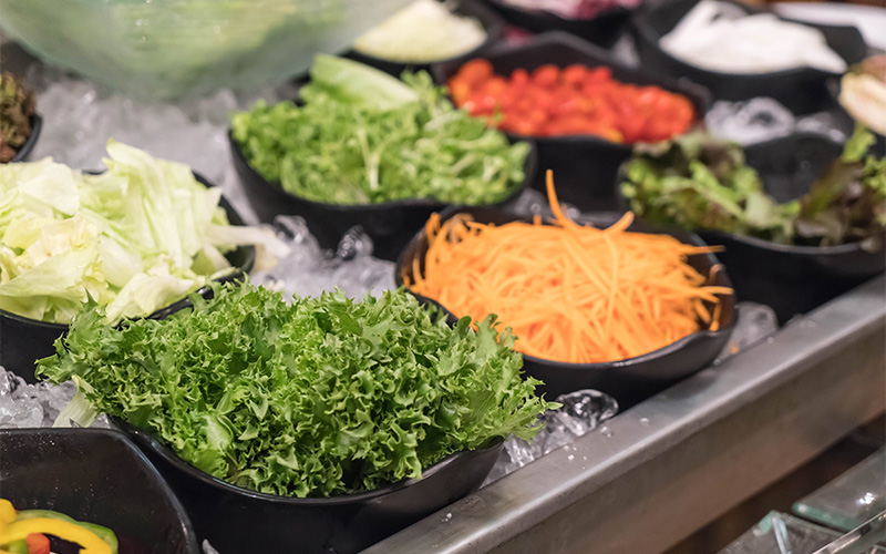Salad bar counter with a variety of fresh ingredients.