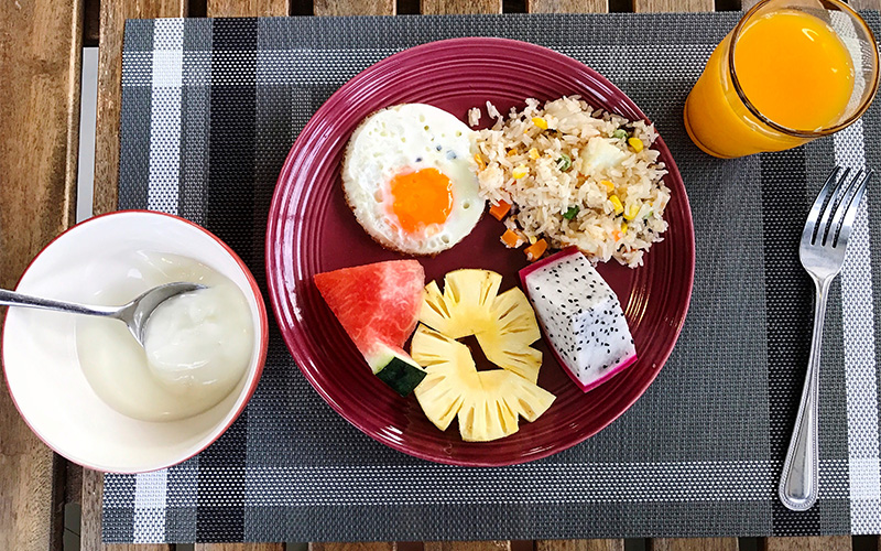 A plate with whole grains, fruits, and eggs on a café table.