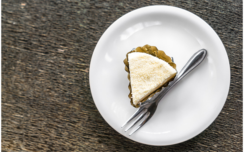 A small slice of cake on a small white plate with a dessert fork.