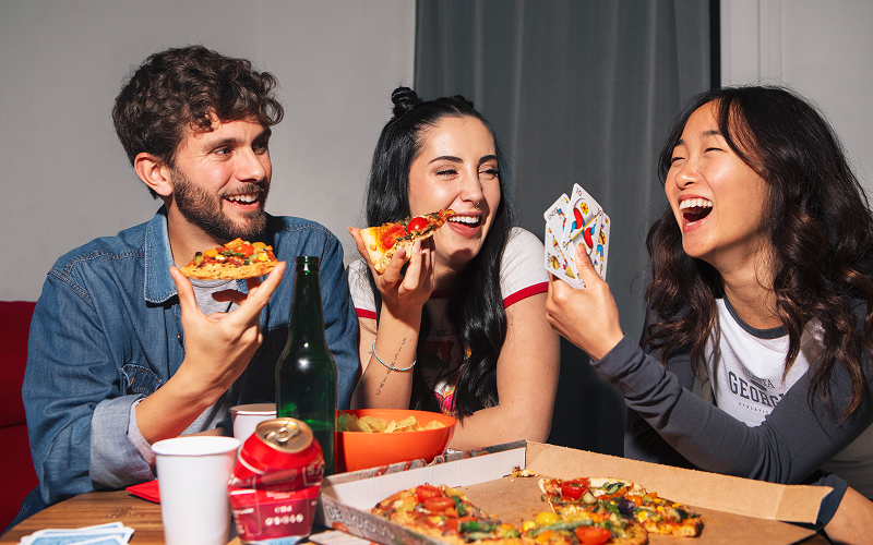 A photo of a group of friends enjoying a pan of pizza