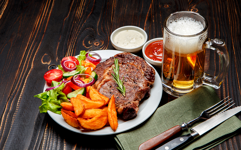 Image of a plate of steak with side dishes and a drink