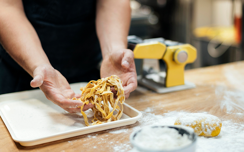 Image of a chef making a fresh noodle dish.