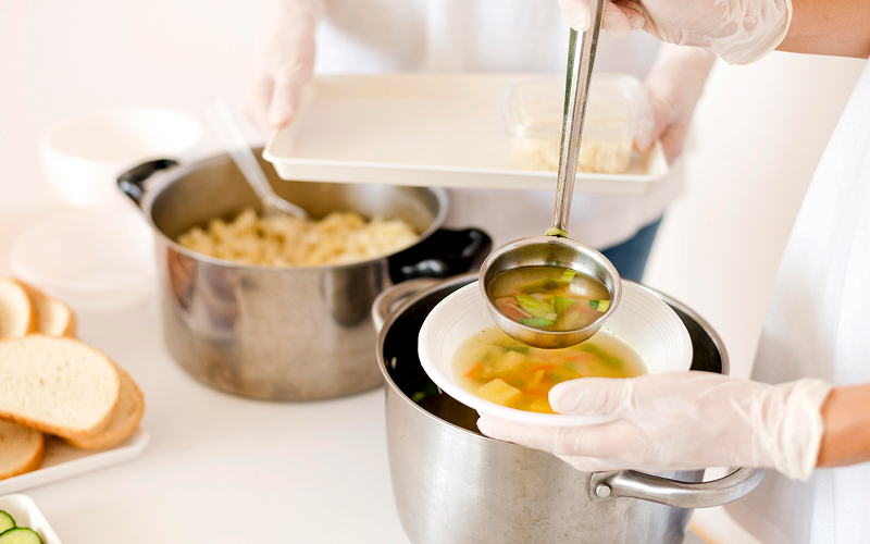 Image of a person adding broth to a bowl.