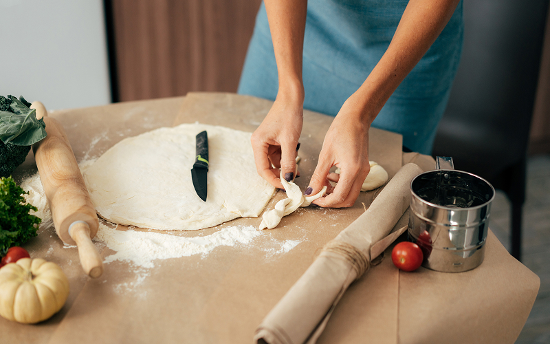Image of a person making pizza dough at home.