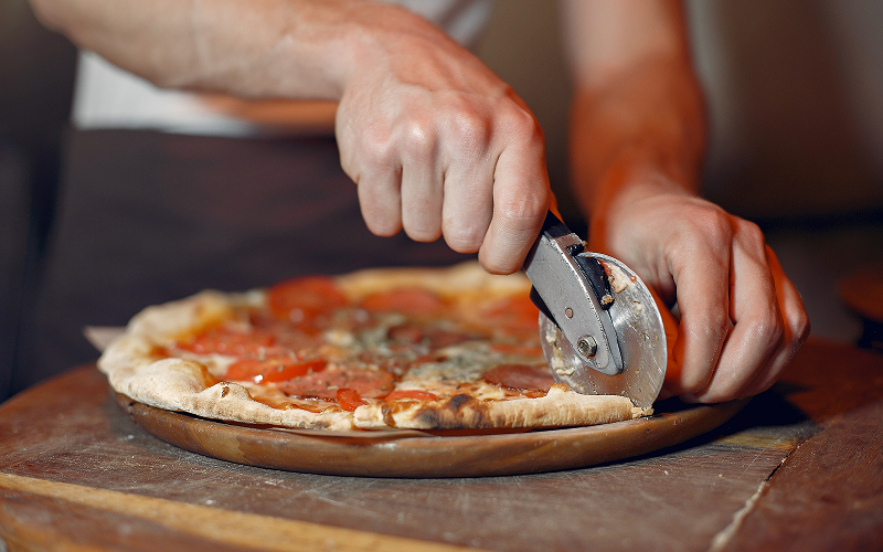Image of a person using a pizza cutter.