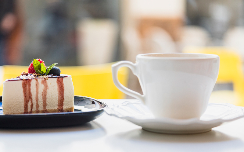 Image of a cup of coffee with a slice of cheesecake