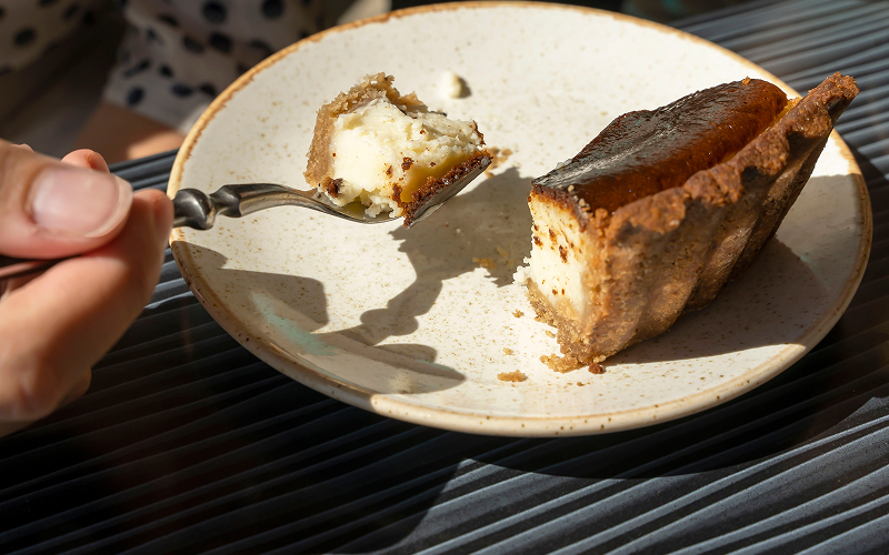 Image of someone taking a slice of burnt cheesecake