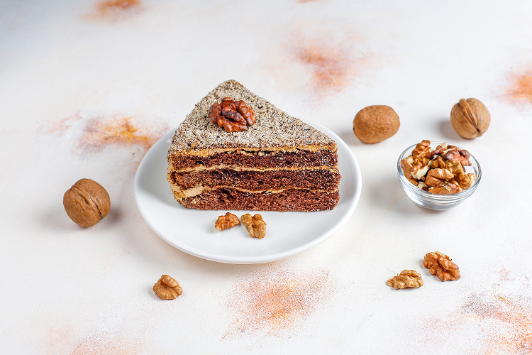 a slice of cake on a plate topped with nuts